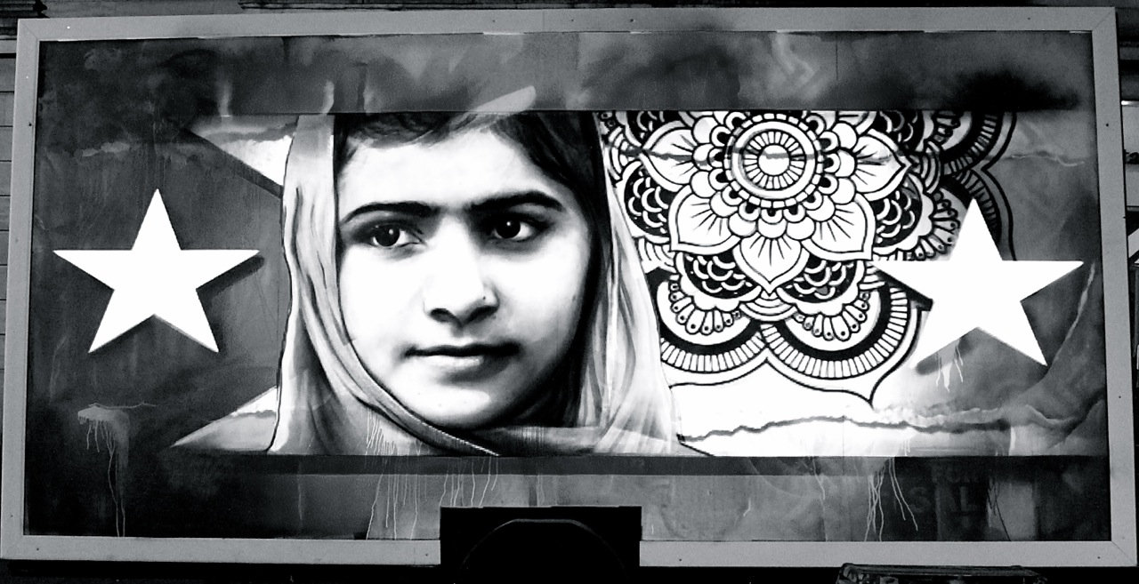 A billboard with an image of a girl wearing a head scarf, with a mandala and stars in the background.